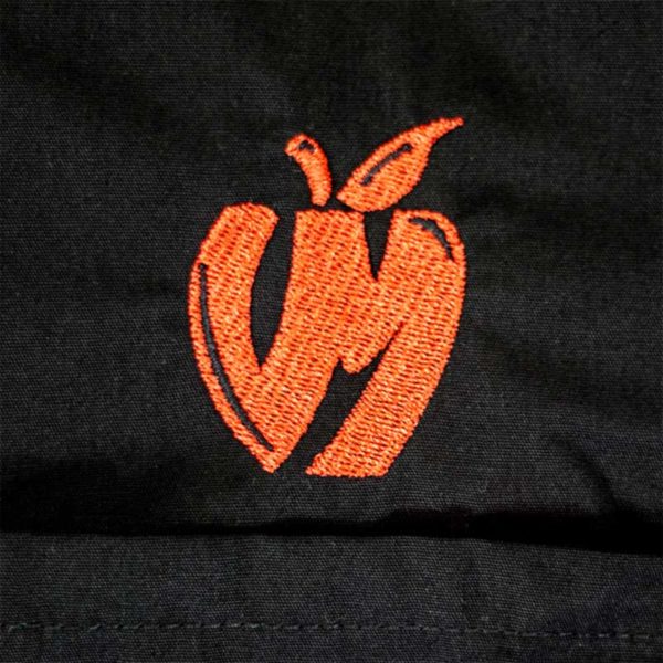 Detail of the embroidered apple logo on the chest of Vander Mill's black snap up work shirt