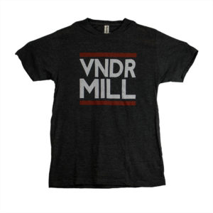 Black t-shirt with "VNDR MILL" in white on the front, thick red lines frame the text from above and below