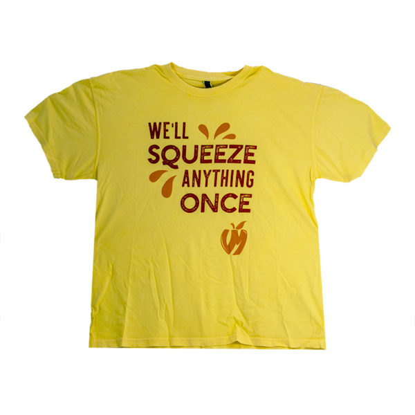 Pale yellow t-shirt with "We'll squeeze anything once" in red with bright orange design elements surrounding the text including a VM apple logo